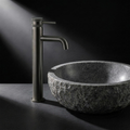 Fonte Basin Mixer Tall in Cast Gunmetal beside a carved granite washbowl