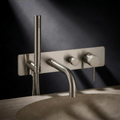 Fonte Wall-Mounted Bath Shower Mixer in Cast Nickel above a carved travertine bath