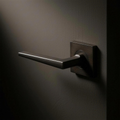 Filo Lever Square mounted on a door in Cast Bronze
