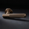 Asta Lever in Cast Bronze, knurled bar lever on a round rose