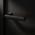 Velo Lever in Cast Black on a flush smoked-oak door