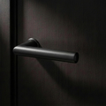 Velo Lever Round in Cast Black on a flush smoked-oak door