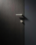 Velo Turn beneath the Velo Lever on a flush smoked-oak door, Cast Nickel